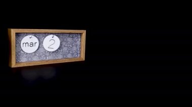 A wooden calendar block showing the date March 22nd with a mans hand putting on and taking off the metal discs with the date and month on them, filmed in 8k quality