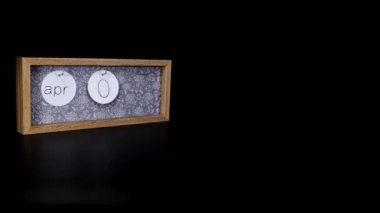 A wooden calendar block showing the date April 6th with a mans hand putting on and taking off the metal discs with the date and month on them, filmed in 8k quality.