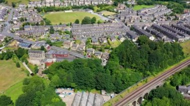 Aerial drone footage of a scenic view of the village of Slaithwaite in the town of Huddersfield in the UK taken with a drone on a hot sunny summers day, showing housing estates and train tracks.