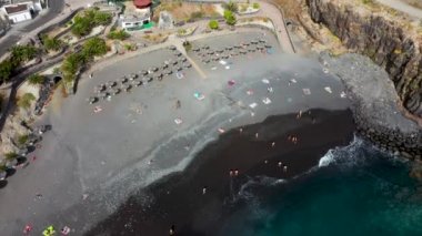 Costa Adeje, Santa Cruz de Tenerife 'nin hava aracı görüntüleri. Playa de Ajabo plajını gösteriyor. İnsanlar siyah kumsalda rahatlıyor ve eğleniyorlar..