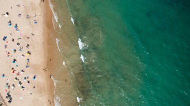 Portekiz 'in Albufeira şehrindeki güzel bir kasabanın havadan çekilmiş fotoğrafı. Praia de Albufeira plajını ve sıcak yaz günlerinde plajda dinlenen insanları gösteriyor.