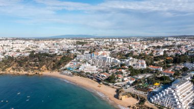 Portekiz 'in Albufeira şehrindeki Albufeira şehrinin havadan çekilmiş fotoğrafı Praia da Oura altın kumlu plajını gösteriyor, şehirde oteller ve apartmanlar var, yaz günlerinde çekilmiş..