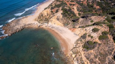 Portekiz 'in Albufeira şehrindeki güzel plajın havadan çekilmiş fotoğrafı sıcak bir yaz gününde okyanus kıyısında tenha bir sahili gösteriyor..