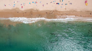 Portekiz 'in Albufeira şehrindeki güzel bir kasabanın havadan çekilmiş fotoğrafı. Praia da Oura plajını gösteriyor ve insanlar sıcak yaz günlerinde plajda dinleniyorlar..