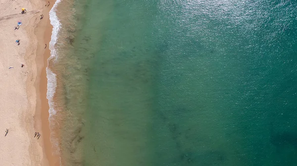 Portekiz 'in Albufeira şehrindeki güzel bir kasabanın havadan çekilmiş fotoğrafı. Praia de Albufeira plajını ve sıcak yaz günlerinde plajda dinlenen insanları gösteriyor.