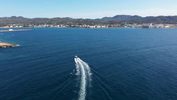 スペインのバレアレス諸島の一つ イビサ島の西海岸にあるサンアントニ ポルトマンの町の空中ドローン映像は 夏の時間に海の中で速いスピードボートを示しています — ストック動画