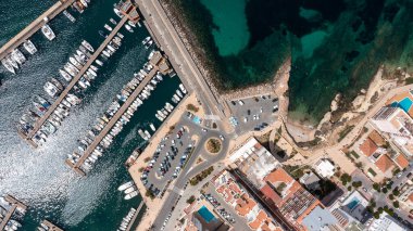 İspanya 'nın Balear Adaları' ndaki İbiza adasındaki Sant Antoni kasabasının hava aracıyla çekilmiş resmi, otoparkın yanındaki teknelerin olduğu limanı gösteriyor..