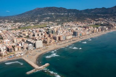 İspanya 'nın Malaga kıyı kasabası Fuengirola' nın önündeki güzel sahil insansız hava aracı fotoğrafı, arka planda dağlar olan kumlu sahil, oteller ve daireleri gösteriyor.