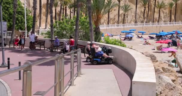 ベニドーム スペイン 2023年7月1日 スペインのベニドームの美しい街の映像は 休暇中にビーチの移動スクーターに座って日光を楽しむ2人の高齢者を示しています — ストック動画