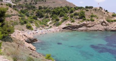 İspanya 'nın Benidorm şehrinin güzel bir görüntüsü. Meşgul Cala Almedraba plajında insanlar yaz tatilinde plajda güneşleniyor ve dinleniyor.