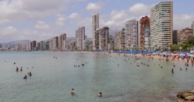 Benidorm İspanya, 1 Temmuz 2023: İspanya 'nın güzel Benidorm şehrinin, plajda dinlenen ve güneşlenen insanlarla dolu Playa de Levante plajını gösteren görüntüsü