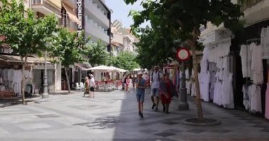 Benidorm İspanya, 1 Temmuz 2023: İspanya 'nın güzel Benidorm şehrinin görüntüleri, Eski Şehir' de gezici scooterla gitar çalan bir adamla sokakta yürüyen insanları gösteriyor.