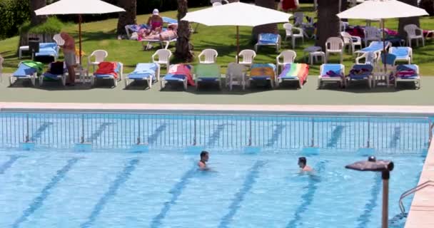 ベニドルムスペイン 7月1日2023 夏の晴れた日にスペインのベニドルム市のホテルのスイミングプールで遊ぶリラックスして日光浴をしている人々の映像 — ストック動画