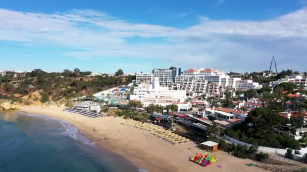 ポルトガルのアルブフェイラの美しいビーチフロントの航空映像 プラリア オラビーチと晴れた夏の日に黄金の砂浜に衝突する波を示しています — ストック動画