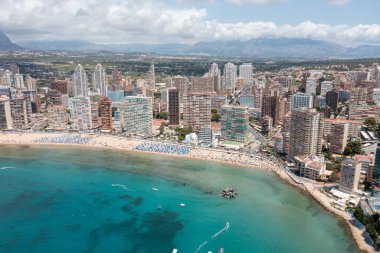 Yazın İspanya 'nın Benidorm şehrinin hava aracı fotoğrafı Playa de Levante plajını ve yaz aylarında şehirdeki yüksek katlı apartman ve otelleri gösteriyor.