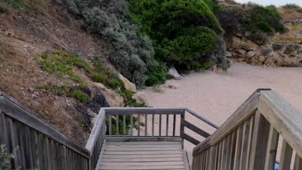夏の暑い晴れた日にポルトガルのアルブフェイラのプライア オラビーチと呼ばれるビーチにつながる木製の階段を歩いている誰かの映像 — ストック動画