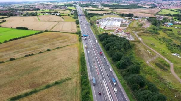 イギリスのウェストヨークシャー州リーズ市にあるイースト アーズリーの村の空撮映像は 夏の間に忙しい高速道路を示している — ストック動画