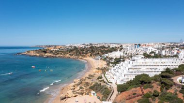 Portekiz 'in Albufeira şehrindeki Albufeira şehrinin havadan çekilmiş fotoğrafı Praia da Oura altın kumlu plajını gösteriyor, şehirde oteller ve apartmanlar var, yaz günlerinde çekilmiş..