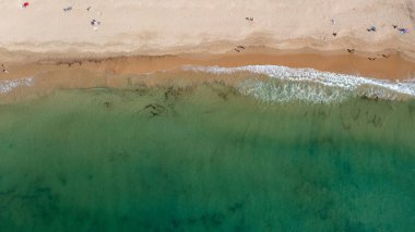 Portekiz 'in Albufeira şehrindeki güzel bir kasabanın havadan çekilmiş fotoğrafı. Praia da Oura plajını gösteriyor ve insanlar sıcak yaz günlerinde plajda dinleniyorlar..