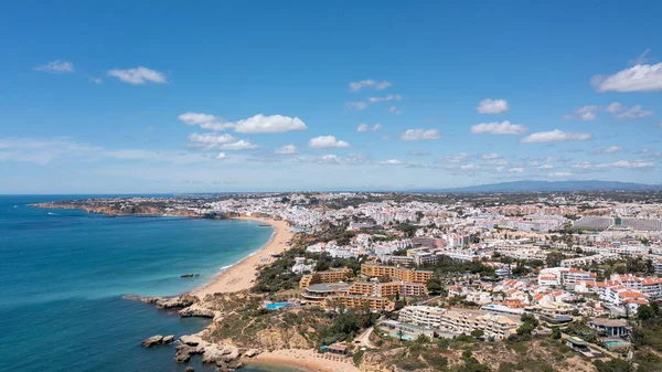 Portekiz 'in Albufeira şehrindeki Albufeira şehrinin havadan çekilmiş fotoğrafı Praia da Oura altın kumlu plajını gösteriyor, şehirde oteller ve apartmanlar var, yaz günlerinde çekilmiş..