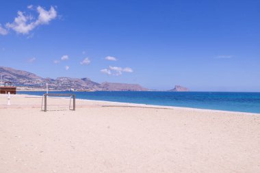 Albir, Altea, Alicante 'deki güzel plajın fotoğrafı Playa de Cap Blanch olarak bilinen plajın kıyısındaki plajda futbol ağlarını gösteriyor.