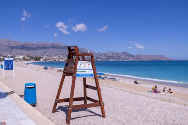 L 'Albir İspanya, 11 Nisan 2024: İspanya' nın L 'Albir kasabasının fotoğrafı güneşli bir yaz gününde kayalık sahil önü ve cankurtaran koltuğunu gösteriyor