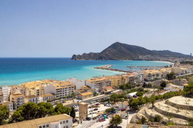 İspanya 'nın Altea şehrinde çekilen hava aracı fotoğrafı tepenin tepesinden çekilmiş ve arka planda okyanus, liman ve dağların bulunduğu tipik İspanyol evlerini gösteriyor.