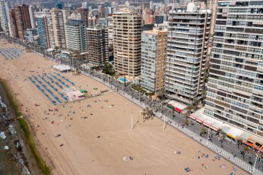 Yazın İspanya 'nın Benidorm şehrinin hava aracı fotoğrafı güneşli bir günde Levante Sahili' nin yanındaki yüksek katlı daireleri ve binaları gösteriyor.