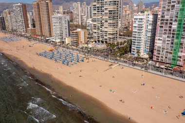 Yazın İspanya 'nın Benidorm şehrinin hava aracı fotoğrafı güneşli bir günde Levante Sahili' nin yanındaki yüksek katlı daireleri ve binaları gösteriyor.