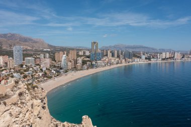 İspanya 'nın Benidorm şehrinin yazın çekilmiş görüntüleri güneşli bir günde yüksek katlı daireleri ve batı sahili boyunca inşa edilen uzun sahili gösteriyor.