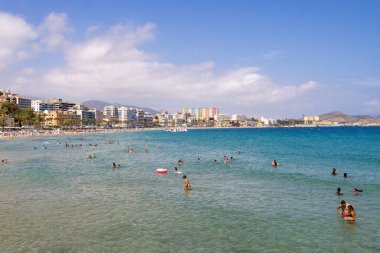 Villajoyosa, İspanya 15 Temmuz 2024: Güneşli bir yaz gününde kumlu plajda ve okyanusta turistleri gösteren güzel Villajoyosa köyünün fotoğrafı