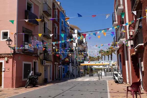 Villajoyosa İspanya, 15 Temmuz 2024: İspanya 'nın güzel bir kasabası olan Villajoyosa' nın fotoğrafı, İspanya 'nın yazları her iki tarafında renkli evler bulunan küçük bir caddeyi gösteriyor.