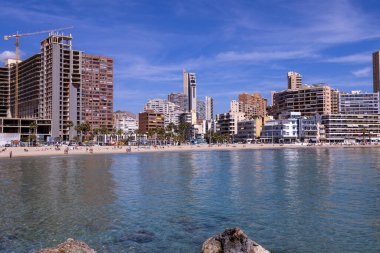Yazın İspanya 'nın Benidorm kasabasının fotoğrafı Playa de Finestrat olarak bilinen plajı ve küçük kumsalın etrafındaki otel ve daireleri gösteriyor.