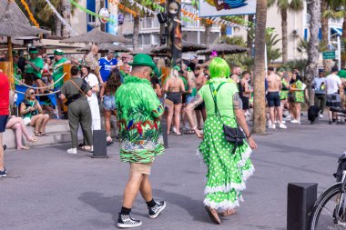 Benidorm İspanya, 17 Mart 2024: İspanya 'da Benidorm' da çekilen fotoğraf, güneşli bir yaz gününde plaj cephesinde Aziz Patrick Günü 'nü kutlayan insanları gösteriyor..
