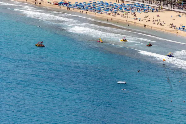 stock image Photo of the city of Benidorm in Spain in the summer time showing people on the famous Levante Beach and children's boats and pedalos being used in the ocean on a sunny summers day