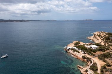 Aerial drone photo of a beach in the town of Sant Antoni de Portmany on the island of Ibiza Balearic Islands Spain showing the ocean front and Cala Alto de Porta beach in the summer time. clipart