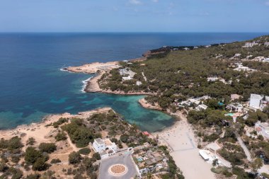İspanya 'nın Balear Adaları' ndaki İbiza adasındaki bir plajda güneşlenen insanlarla sahili gösteren insansız hava aracı fotoğrafı..