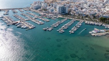 İspanya 'nın Balear Adaları' ndaki İbiza adasındaki Sant Antoni kasabasının insansız hava aracı fotoğrafı oteller ve dairelerle dolu teknelerle dolu tekne limanını gösteriyor..