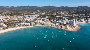 Aerial drone photo of a beach in the town on the island of Ibiza in the Balearic Islands Spain showing the beach with people sunbathing. clipart