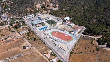 Aerial drone photo of a sports stadium in the town of Sant Antoni de Portmany on the island of Ibiza in the Balearic Islands Spain, showing the running track stadium in the summer time. clipart