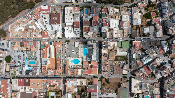 Прямо вниз arial drone photo of the town of Sant Antoni de Portmany on the west coast of Ibiza one of Spains Balearic Islands, showing hotels, apartments and businesses on the village in the summer