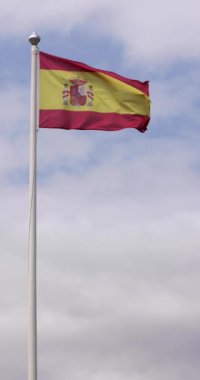 Güneşli bir yaz gününde rüzgarda dalgalanan İspanyol bayrağının ağır çekimde çekilmiş portre görüntüleri.