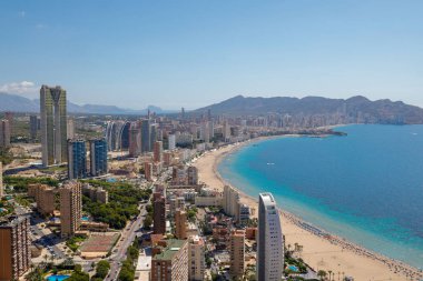 İspanya 'nın güzel Benidorm şehrinin hava aracı fotoğrafı güney sahil geçidini, otelleri ve arka planda kumlu uzun plajlı apartmanları gösteriyor.