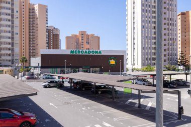 Benidorm İspanya, 3 Haziran 2024: İspanya 'daki Benidorm şehrinin fotoğrafı, Mercadona' daki ünlü süpermarket binasını ve yazın şehir merkezinde gölgeli arabalı büyük bir otoparkı gösteriyor.