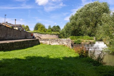 Photo of the beautiful town of Bedale, which is a market town and civil parish in North Yorkshire, England showing the Bedale Beck and waterfall on a hot sunny day in the summer time clipart