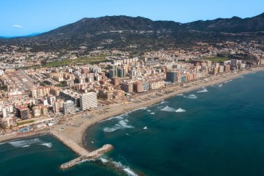 İspanya 'nın Malaga kıyı kasabası Fuengirola' nın önündeki güzel sahil insansız hava aracı fotoğrafı, arka planda dağlar olan kumlu sahil, oteller ve daireleri gösteriyor.