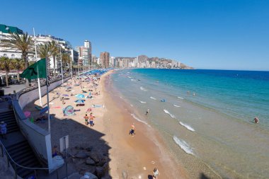 Benidorm İspanya, 22 Haziran 2024: İspanya 'nın Benidorm kentindeki ünlü Levante Sahili' nin fotoğrafı sıcak bir yaz gününde turistlerle dolu yoğun plajı gösteriyor