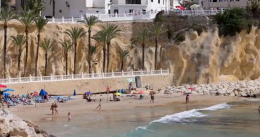Benidorm İspanya, 1 Mart 2024: İspanya 'nın güzel Benidorm şehrinin görüntüsü yoğun Cala del Mal Pas plajını insanların plajda dinlendiği ve yaz tatilinde güneşlendiği
