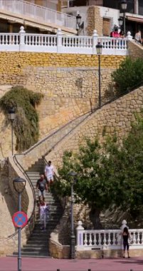 Benidorm İspanya 21 Mart 2024: İspanya 'da Benidorm kasabasının güneşli bir yaz gününde merdivenlerden inip çıkan insanları gösteren portre görüntüleri.