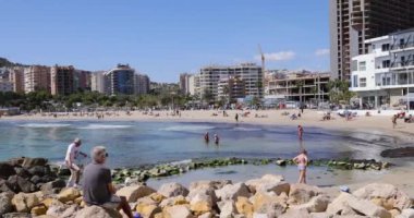 Benidorm İspanya, 15 Mart 2024: İspanya 'nın Benidorm kentinin yaz ayındaki görüntüleri Playa de Finestrat olarak bilinen plajı, küçük sahil çevresindeki otel ve daireleri gösteriyor.